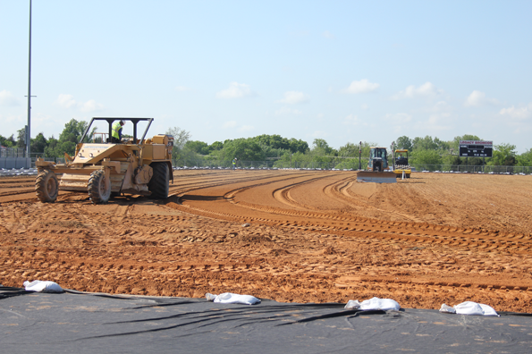 Hellas Construction workers smooth out dirt while preparing the football field for Matrix Turf on April 22. The synthetic material will replace the grass and is expected to be complete by August. With the new material all girls district soccer games and JV football games are set to be played at the home field. (Sterling Greback photo)