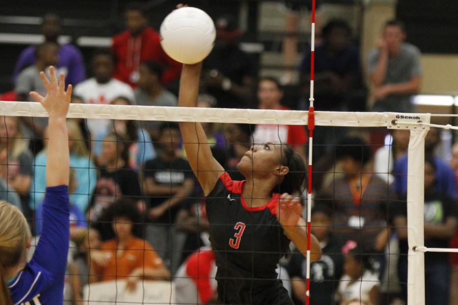 Jasmine Jones, 12, spikes the ball over the net in a volleyball game. 
