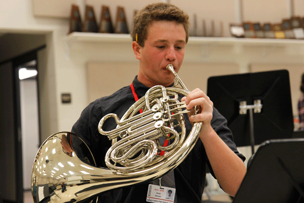 In the band hall, David Darmon, 10, warms up on his French horn before class starts. Darmon was practicing for Region auditions starting in December. (Maddy Brown photo)