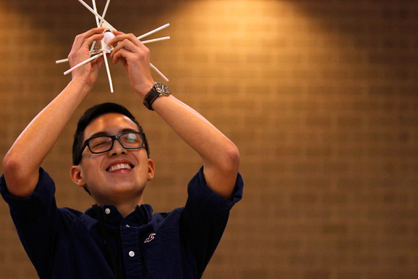 In Mr. Daviss AP Physics class, Alex Rodriguez, 11, drops his groups project over the balcony in attempt to see if they made the protective structure sturdy enough for the egg to survive the fall. (Maddy Brown photo)