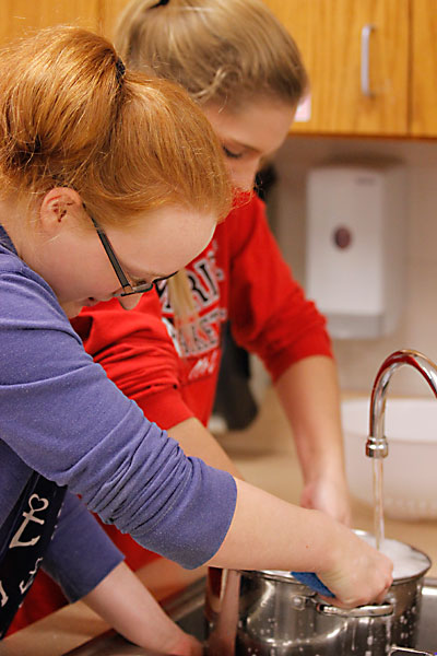 In Ms. Taylors Nutrition class, Dawn Waldrep, 9, and Faith Rusch, 9, wash pots and pans after making fettuccine. (Maddy Brown photo)  