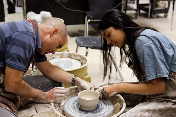Mr. Shane Skinner assists Aiman Khan, 12, with shaping her bowl on Feb. 16 in ceramics class. (Maddy Brown photo)
