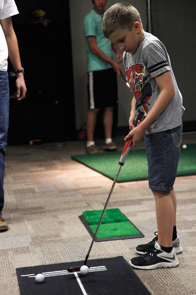 LUCK Week candidate, Christian Spidle, practices putting in the golf room with members from varsity boys golf. The LUCK Week pep-rally will be March 4 and is $1 for admission. (Maddy Brown photo)