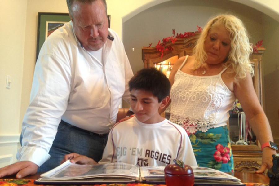 Cooper Certain, 9, looks through a baby scrapbook with his adoptive parents.