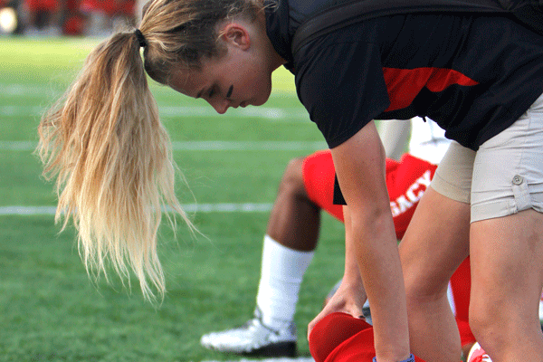 Erin McTighe stretches a football players leg during the homecoming game.
