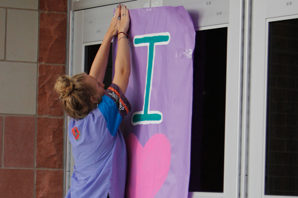 Student Body President, Sadie Johnson hangs a sign for the 80's dance.