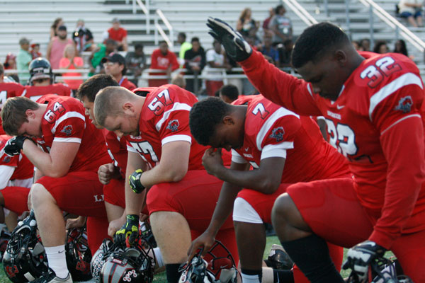 Senior Craig Nealy raises his hand in prayer before a football game.