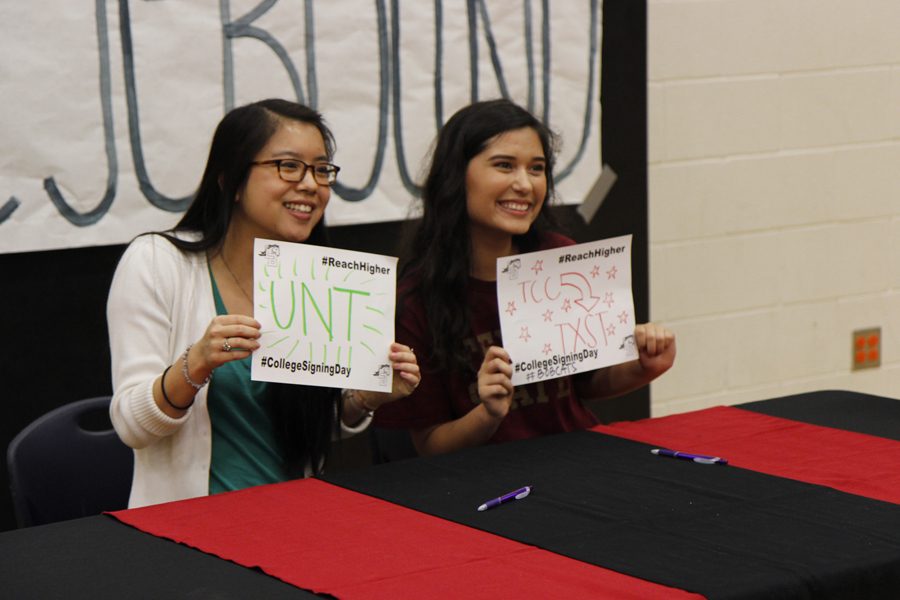 Seniors Fiona Hoang and Sophia Rico hold their college signs at the College Signing Day event in the Legacy JV gym. 