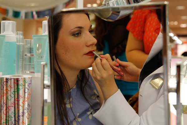 A makeup consultant applies Pop Passion red lipstick onto Makayala Jones lips. 