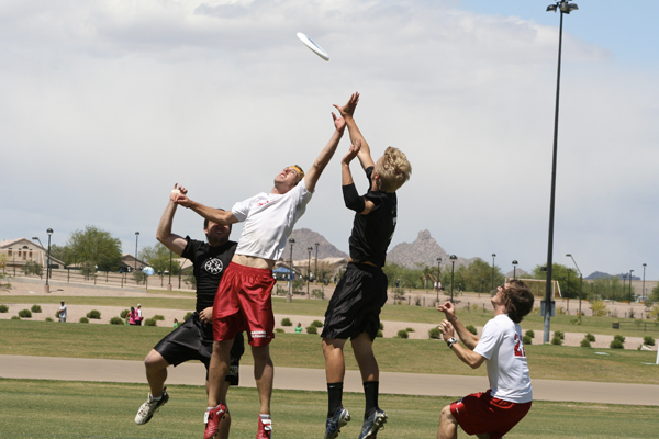 Ultimate frisbee players jump for the frisbee during a game.