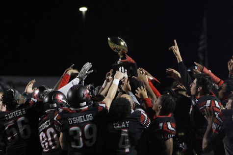Varsity football holds up their trophy after defeating Cleburne 56-21 in the Bi-District  playoff game.
