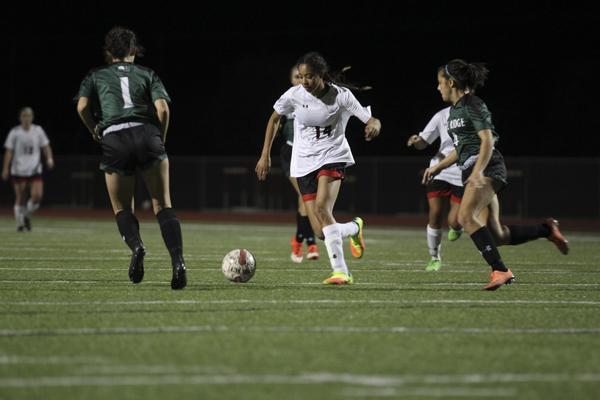 Senior Heaven Conner dribbles the ball through Lake Ridge defenders in a district game.