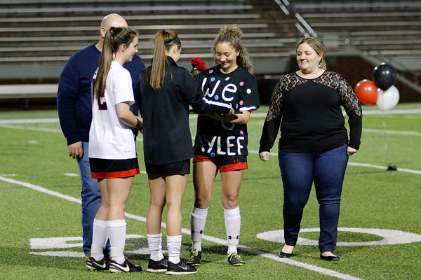 At senior night, Kaylee Wilkinson, 12, receives flowers and a gift from underclassmen teammates. 
