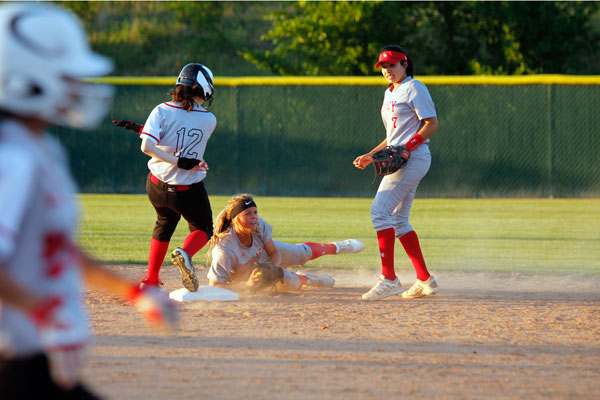 Diving to catch a ball, Meagan Dake, 12, slides past Camryn Aguilar, 11. Dake scanned the infield to see if she could get the out.