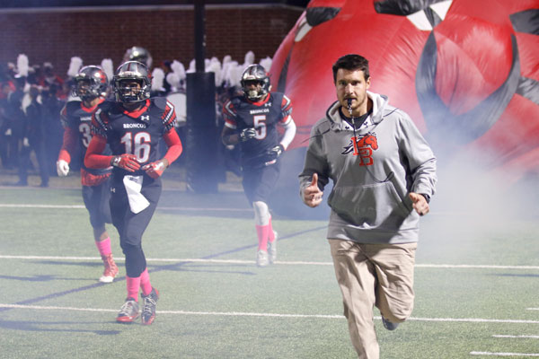 Senior Randy Wright runs out of the tunnel with his teammates and Coach Hamilton Greer. 