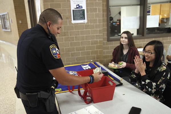 Seniors Ashley Owen and Tiffany Vo cheer as Officer Aaron Rengal donates money to Key Clubs Hurricane Harvey donation drive. Key Club, Student Council, Legacys Nurses, MISD and Journalism teachers are all doing their part to help with Hurricane Harvey relief.