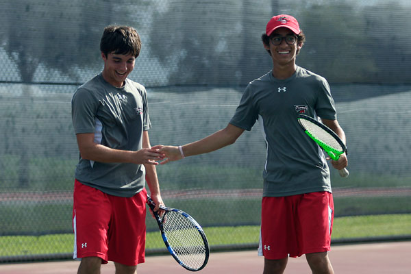 Junior Christian Violette smiles with his teammate at the varsity tennis match against Summit on Oct. 5. 