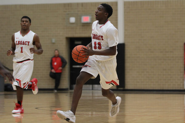 Junior Michael Simmons takes the ball down the court followed by teammate Jalen Catalon, 11 during last year's varsity match against Ennis on Dec. 12. 