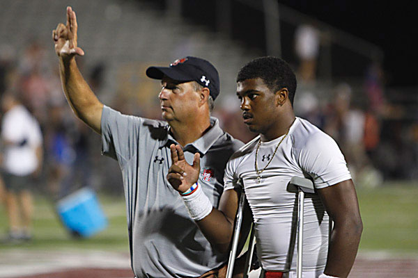 Coach Tim Kilgore and Jalen Catalon, 12, hold up the school hand sign during the alma mater. Legacy lost against Jenks, 35-14. (Ryland Mallett photo)