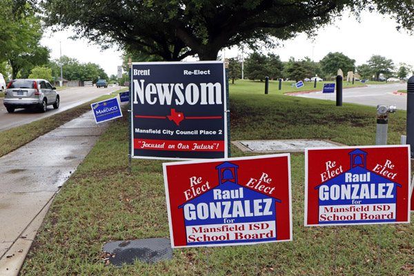 Passing cars view school board and city council election campaign signs outside of the Tarrant County Subcourt house at Mansfield on May 2.