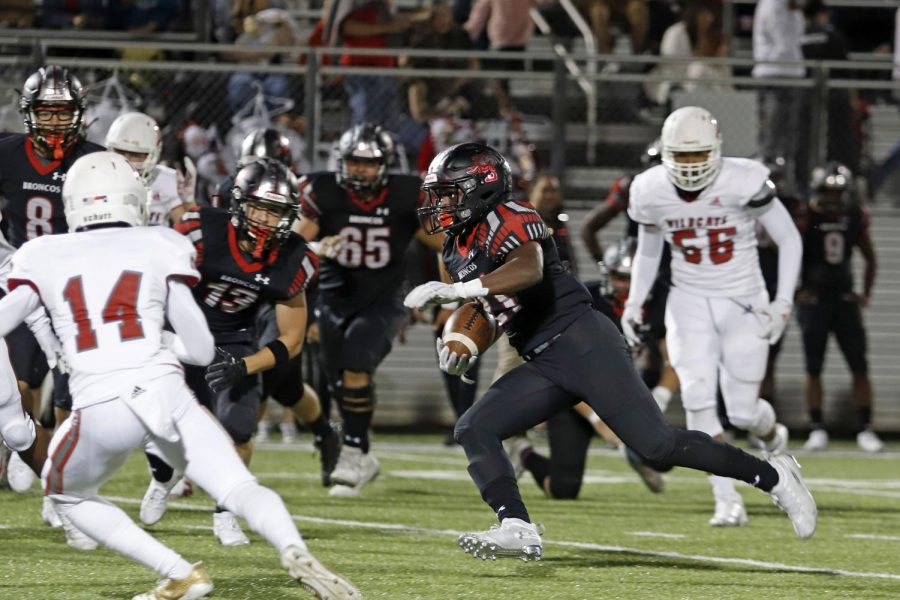 Senior Ayo Adeyi, 21, runs the ball during the Woodrow Wilson game. The Broncos won their first game of the season 35-7.