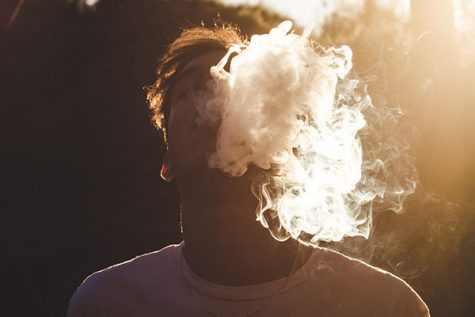 An anonymous man blows smoke after vaping in the sunlight. Courtesy photo by Daniel Ramos on Unsplash.
