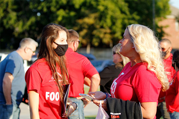 Student Council member, Casey Burkham, talks to a parent at the football game against Eaton High School.