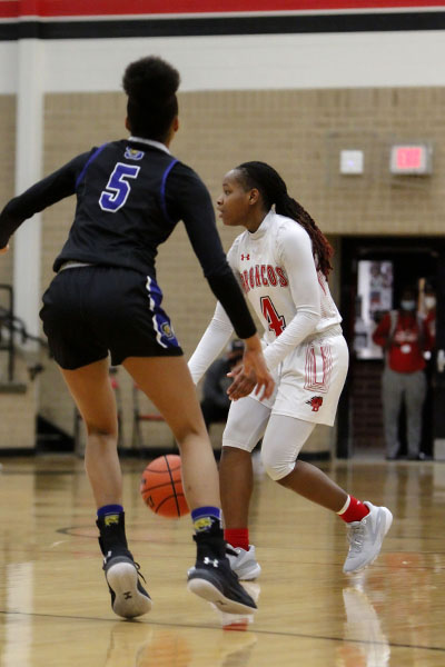 Looking to pass the ball, Sirviva Legions, 11, dribbles across the court. The varsity girls basketball team completed their season undefeated. (Amara Shanks Photo)
