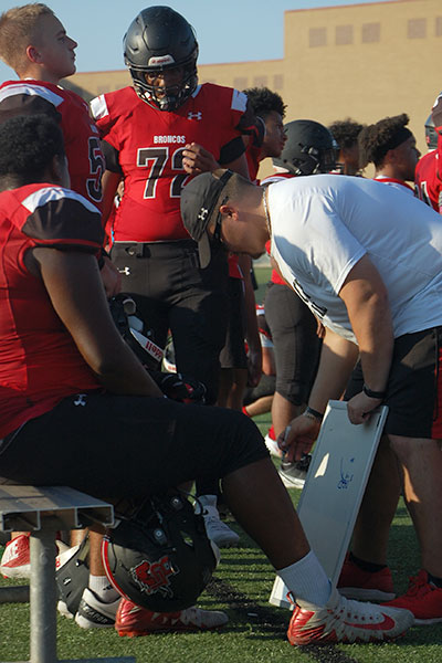 Isaac Green, 10, and Jhett Gordon, 10, huddles with Coach Donahue as he draws up a plan for the Lineman.