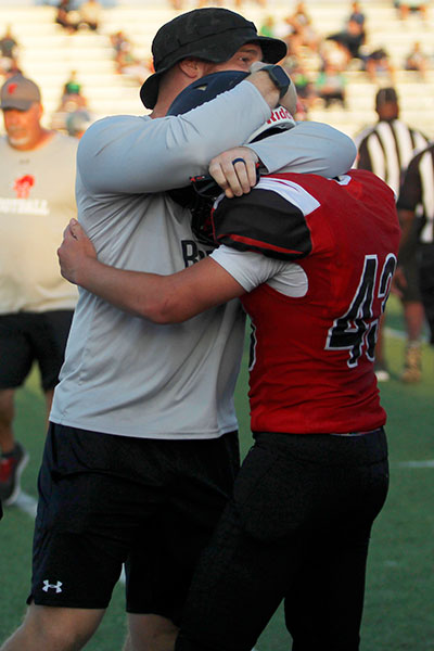 Coach Oliver hugs Nathan Hanes, 10, after a good play. Hanes plays Linebacker for JV.