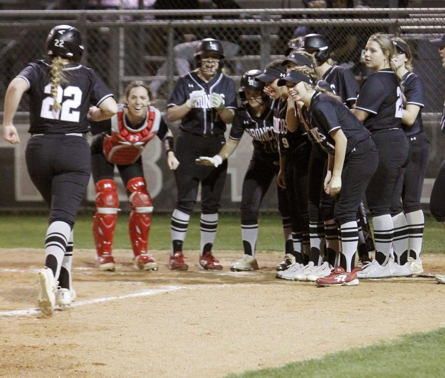 Varsity Softball all join together at home plate to cheer on one of their teammates coming home. 