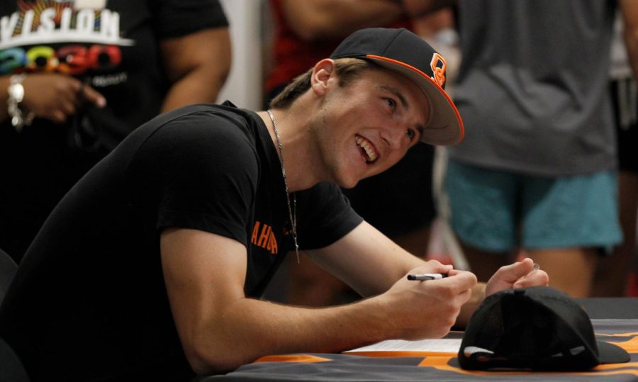 Right before signing his Oklahoma State University Baseball Contract, Blake Julius, 12, smiles and talks with his parents on National Signing Day. After posing for multiple photos he signed his name.