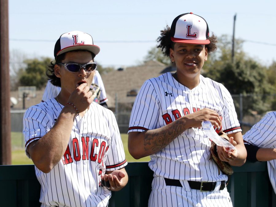 To stay energized, Brandon Young, 11, and Diego Sanchez, 12, stand on the side of the dugout and eat grapes. Young said, “My favorite memory this year is definitely coming in to close a district game against Duncanville to win district champs”. 
