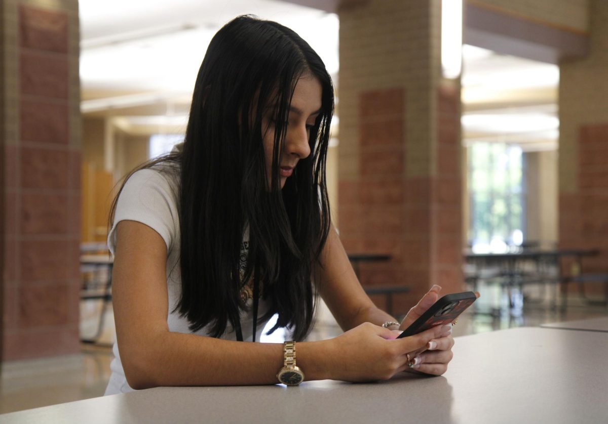 Sophomore Ariel Rodriguez uses her cell phone during lunch. Per the updated policy issued my the Board of Trustees, cell phones, mobile devices, smartwatches and headphones are to remain off and out of sight during all class periods. Students are only able to use their device during passing period and lunch.