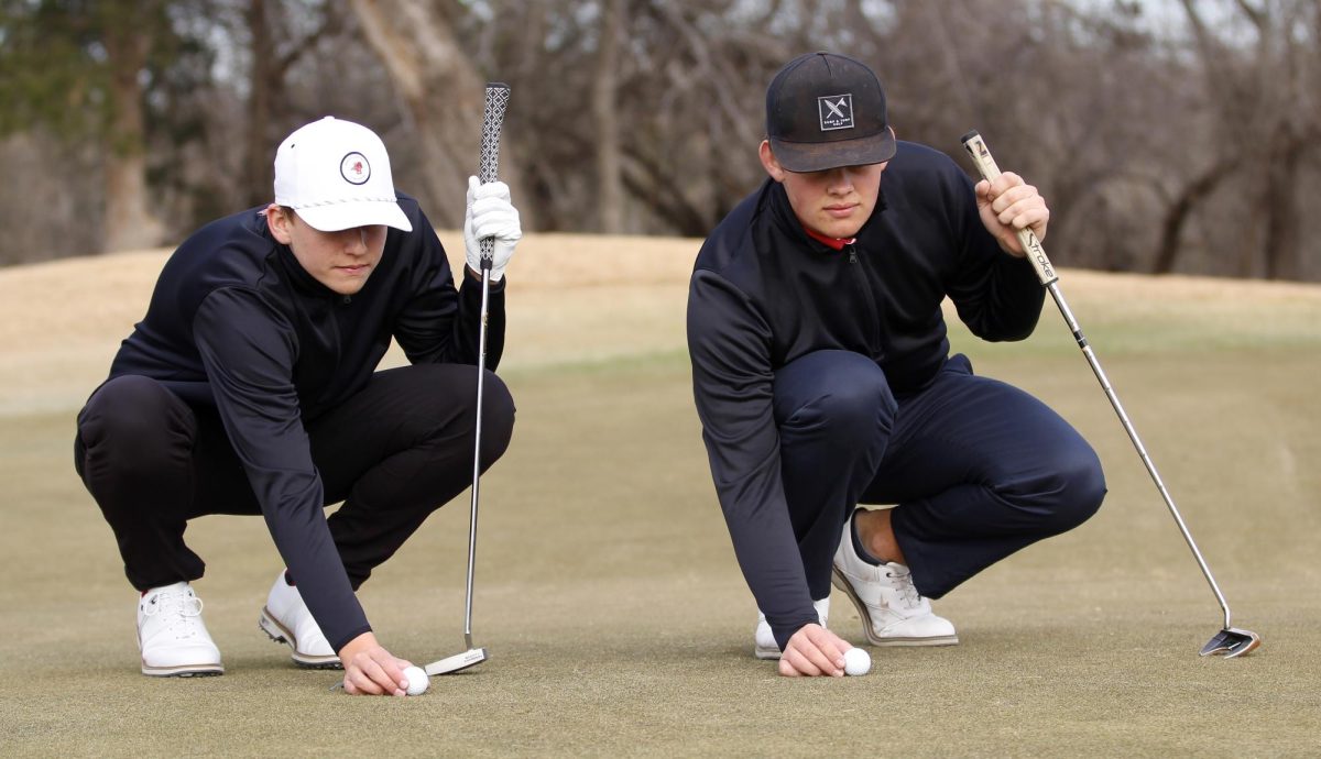 Juniors Caiden Cooper and Carson Hardaway eye their golf balls on the green before putting them on Dec. 3, 2022. [File Photo]