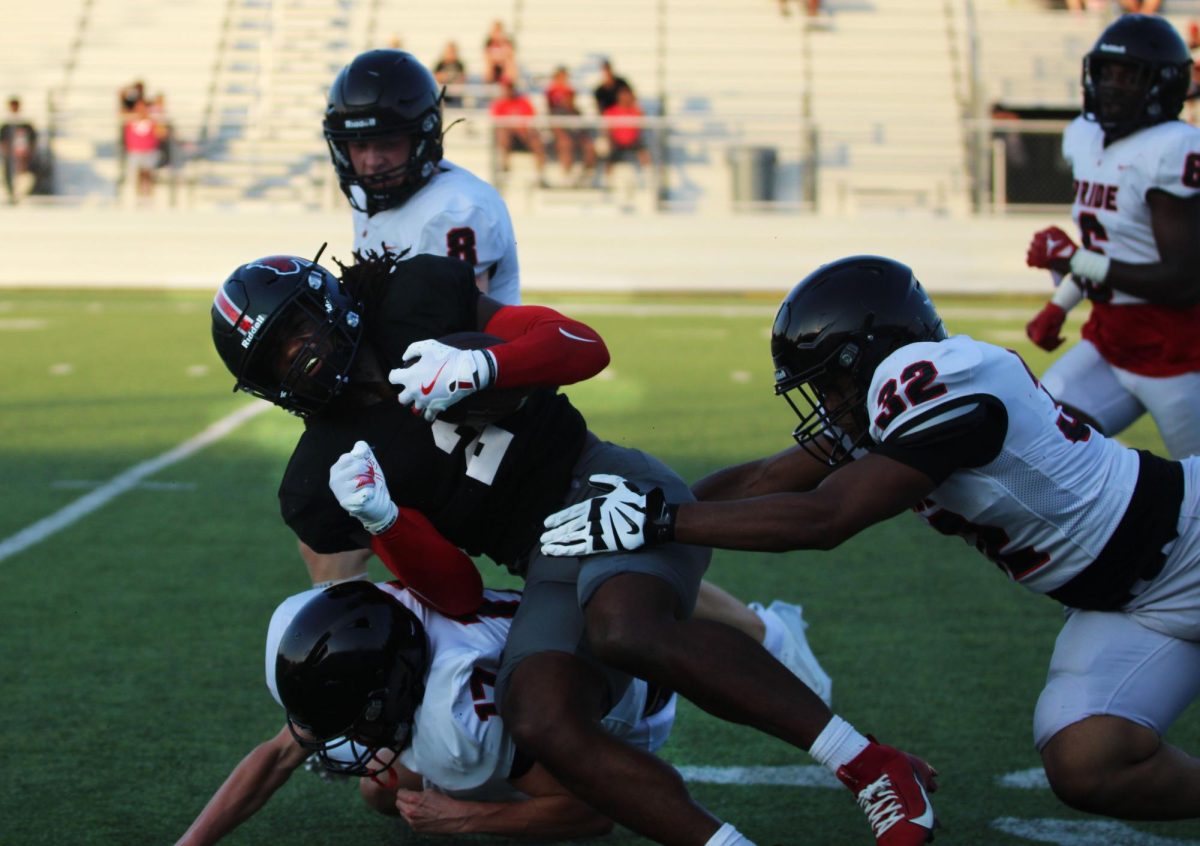 As player, Jaden Manning, 12, catches the ball opponents swarm and tackle him.