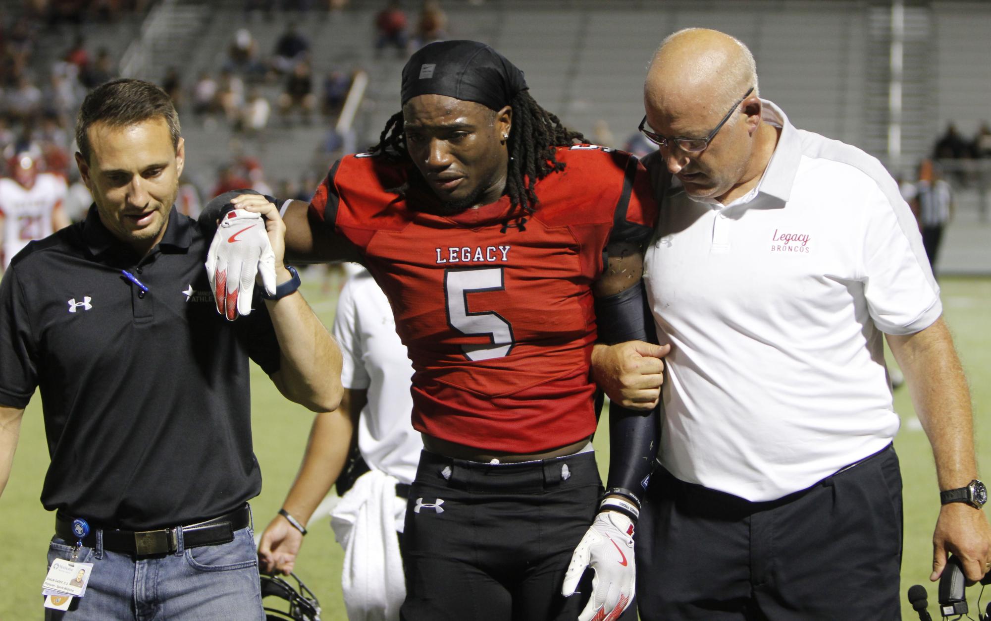 Jaden Manning, 12, gets led off the field by Head Coach Jeff Hulme and team doctor Shaun Garff after fracturing his fibula in a game against Justin Northwest on Aug. 30. Manning expects to return after a two week recovery process, including a week in a medical boot. "For me, [the injury] wasn't the problem," Manning said. "It was the fact that I wanted to play because my body didn't hurt, but I just knew something was wrong."