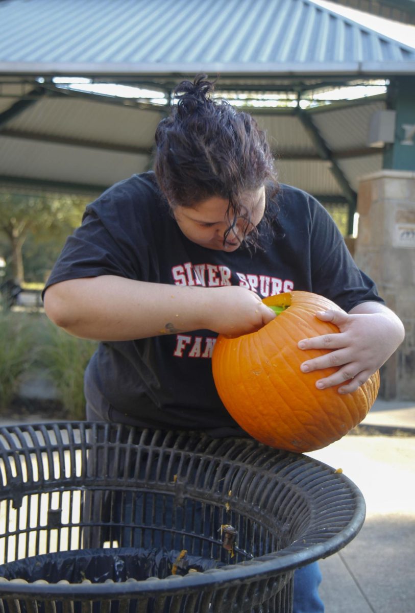 Ms. Martines, one of LDU's sponsors, scrapes out the inside of her pumpkin to prepare it to carve.