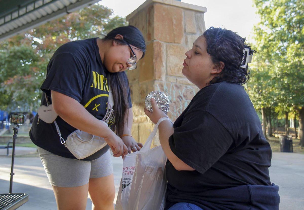 Holding the bag open, Maria Limas, 12, and Ms. Martinez help give out the food to those who ordered from Limas’ family's food truck.