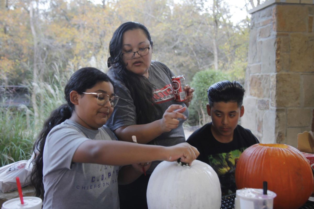 LDU sponsor, Ms. Peña, helps her daughter decide what to add to her pumpkin as her son watches.