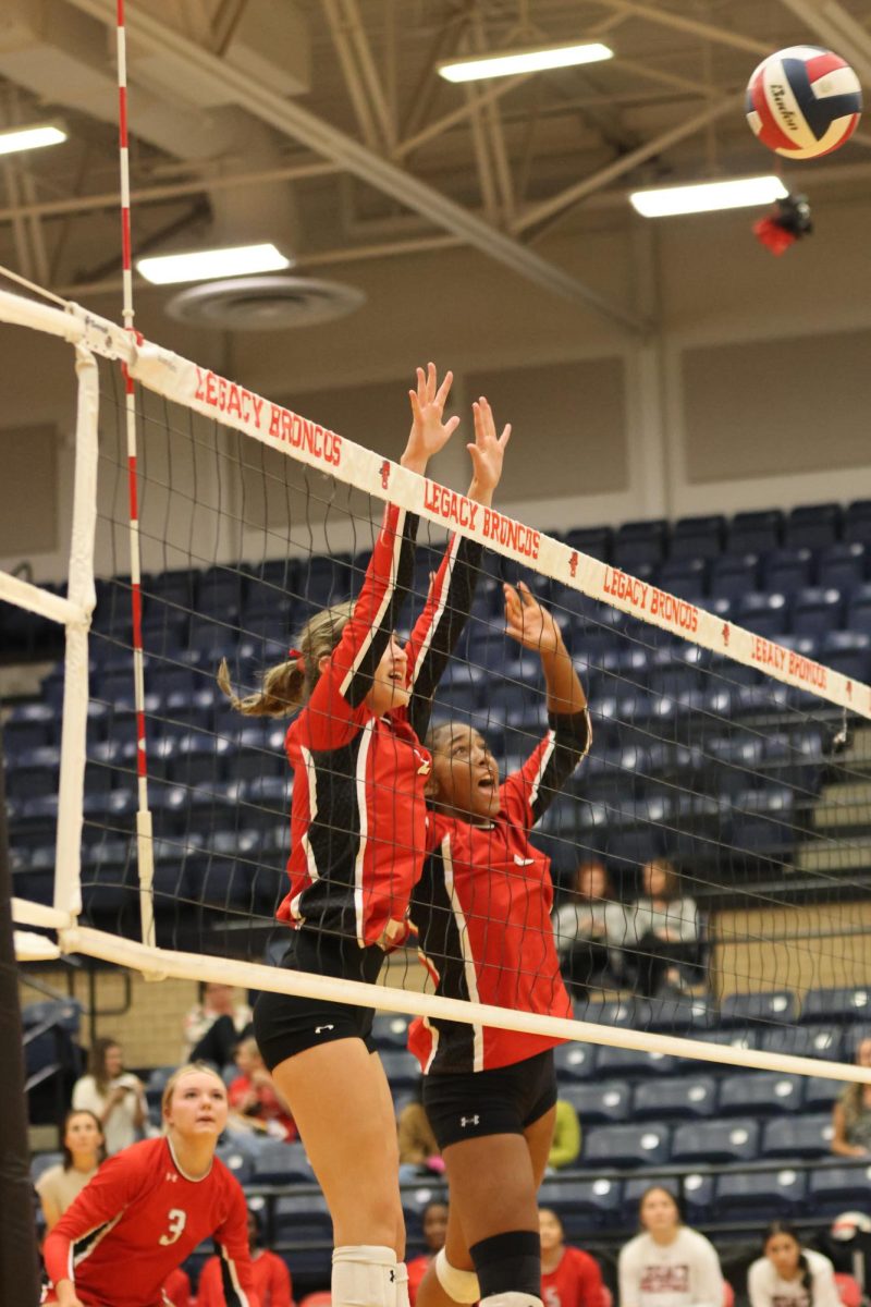 After the serve, Ryleigh Layton, 12, and Elyssa Nunn, 12, jump above the net to block the ball.