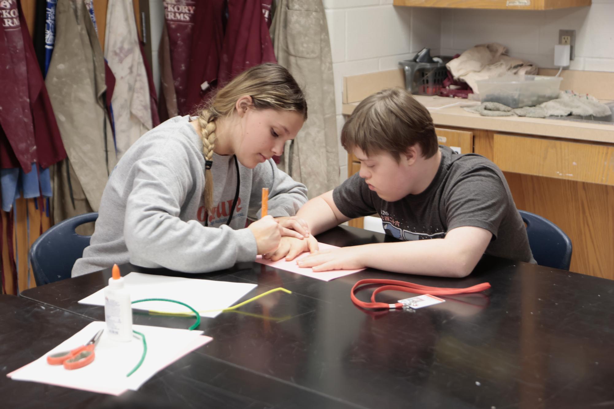 Georgia Topp, 11, traces Nathan Rothwell's, 9, hand during Partners in Art on May 8. 