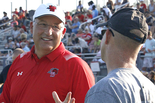 Coach Hulme talks to a parent of a football player. 
