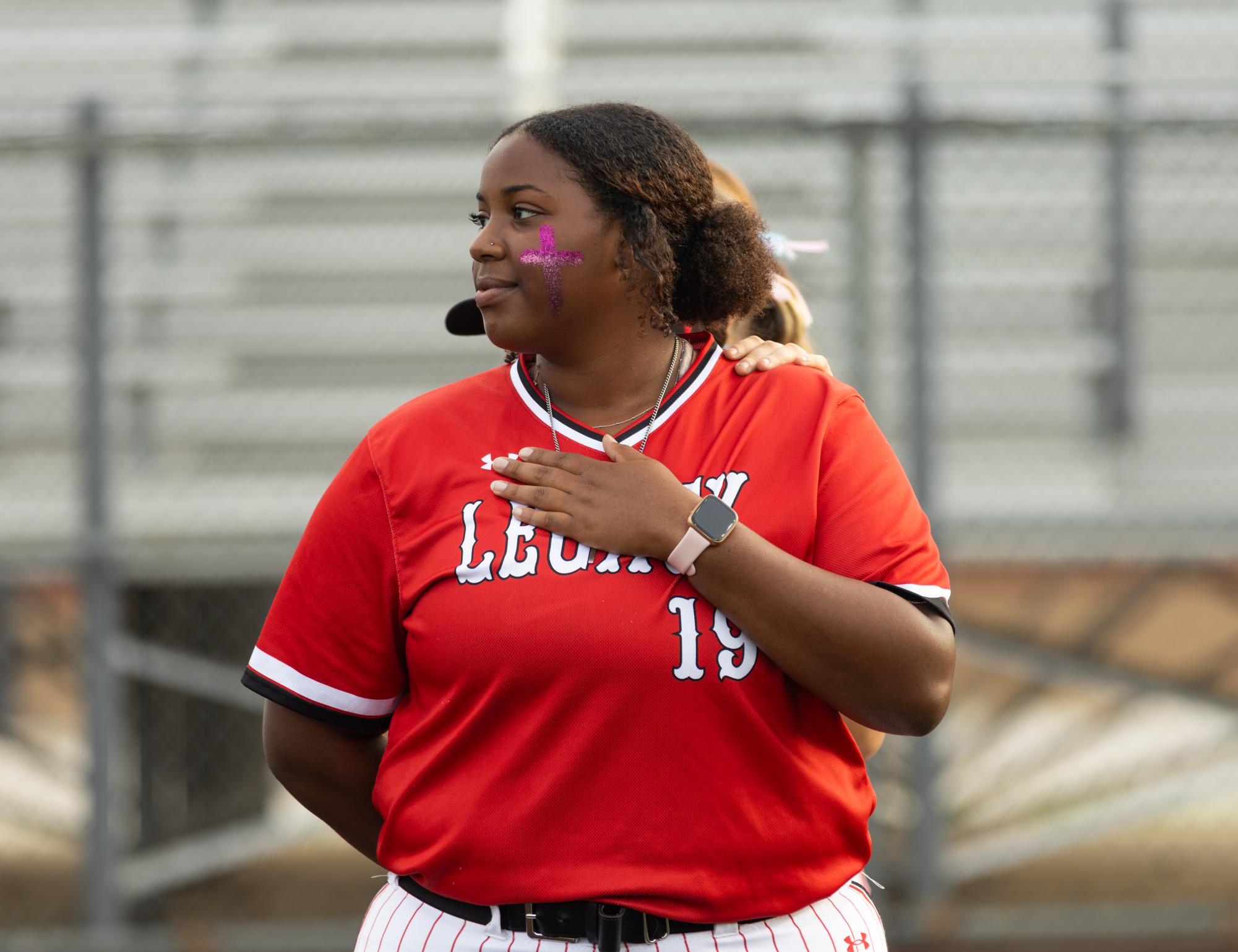 With her hand on her heart, sophomore Cirye Carpenter listens to the national anthem before the game against Mansfield April 7.