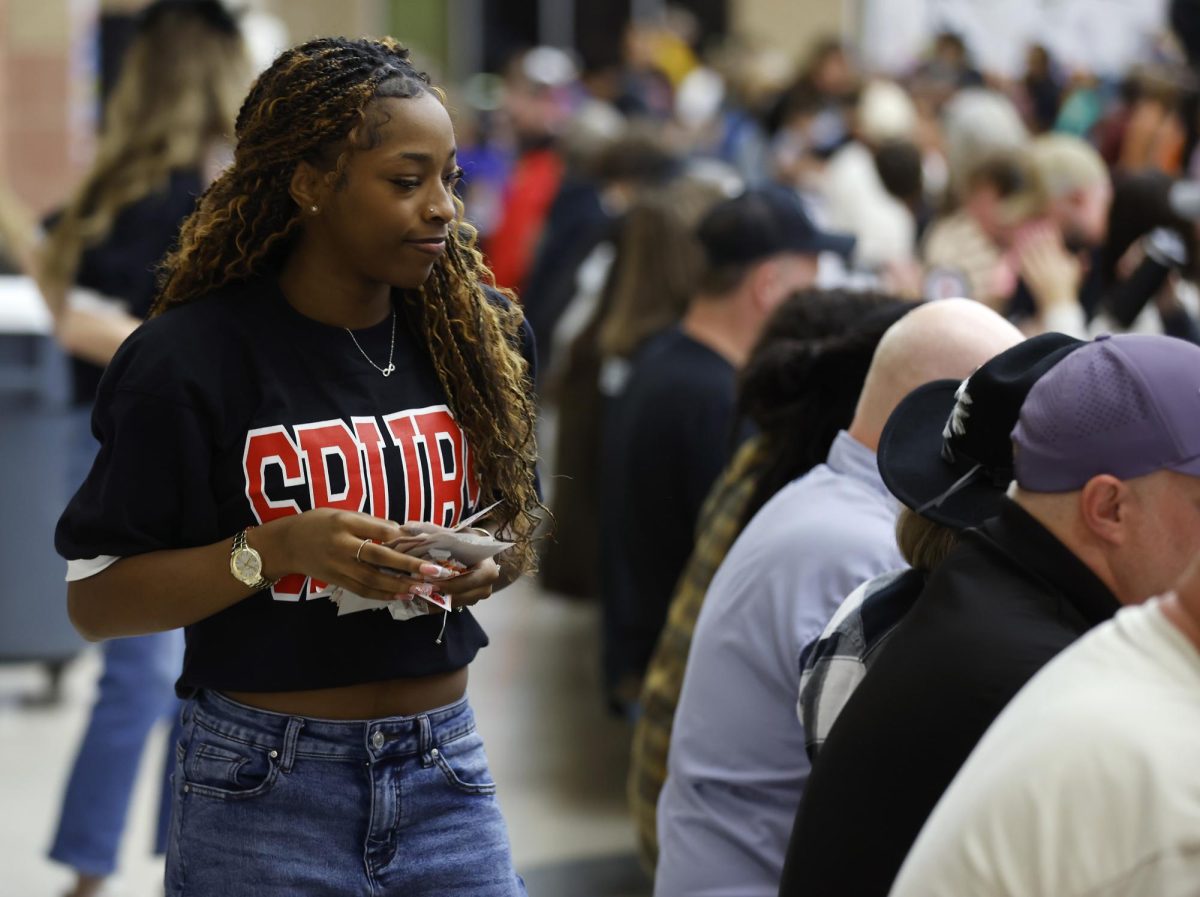Walking down the tables, Trinitee Hall, 11, passes out Bingo cards to drill team family members. Spurs hosted the Bronco Bingo Night on Feb. 7.