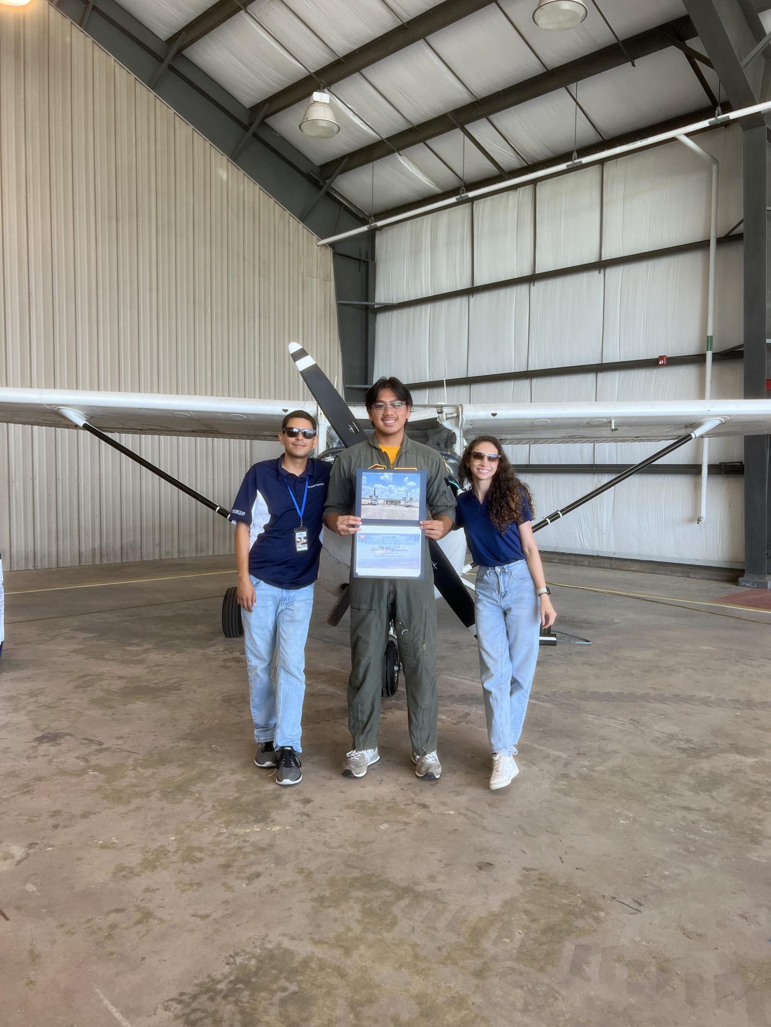 Dave Lopez, 12, stands with his instructors Daniel Urcia and Manuela Diez after completing his first solo flight June 24.