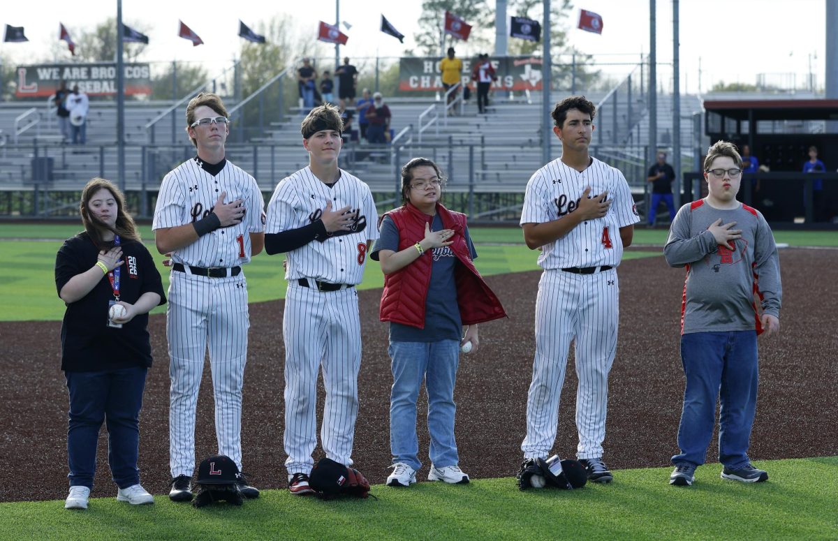 Before the game, Landon Boyer, 12, Grant Peterson, 11, and Ethan Weaver, 10 stand with their partner in PE to sing the national anthem.