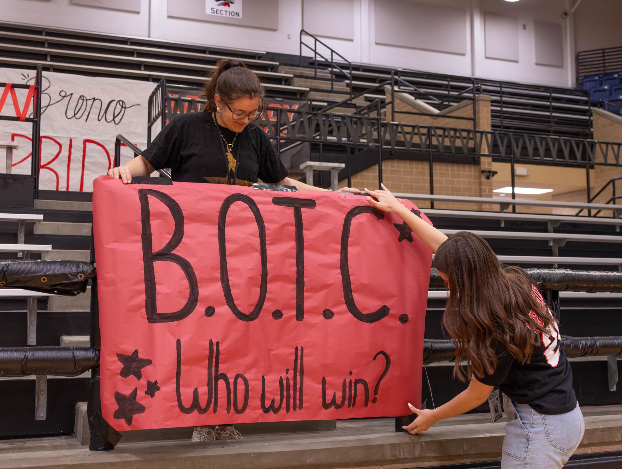 Hanging up a poster, seniors Katherine Keating and Jordyn Green decorate the varsity gym. Student Council will host the Battle of the Classes pep rally on April 10. 