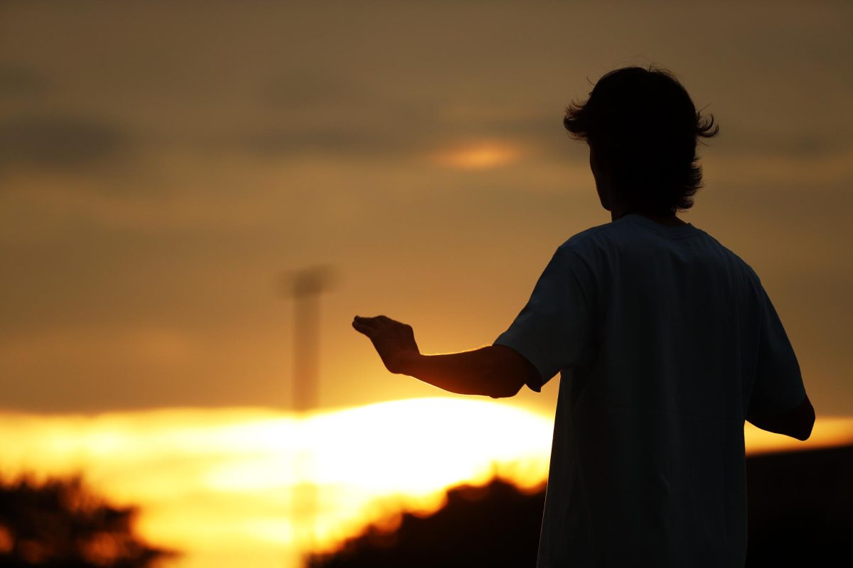 As the sun sets during band practice on Oct. 16, senior drum major Reed Pickering leads and conducts the marching band.